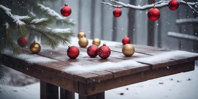The primary subject of the image is a wooden table with a snowy surface. On the table, there are several ornaments, including gold and red Christmas balls, which are the main objects in the scene. The setting is outdoors, with a snowy background, and the visual style appears to be a photo. The colors and mood of the image are predominantly cold and wintry, with the snow and the gold and red ornaments creating a festive yet chilly atmosphere.
